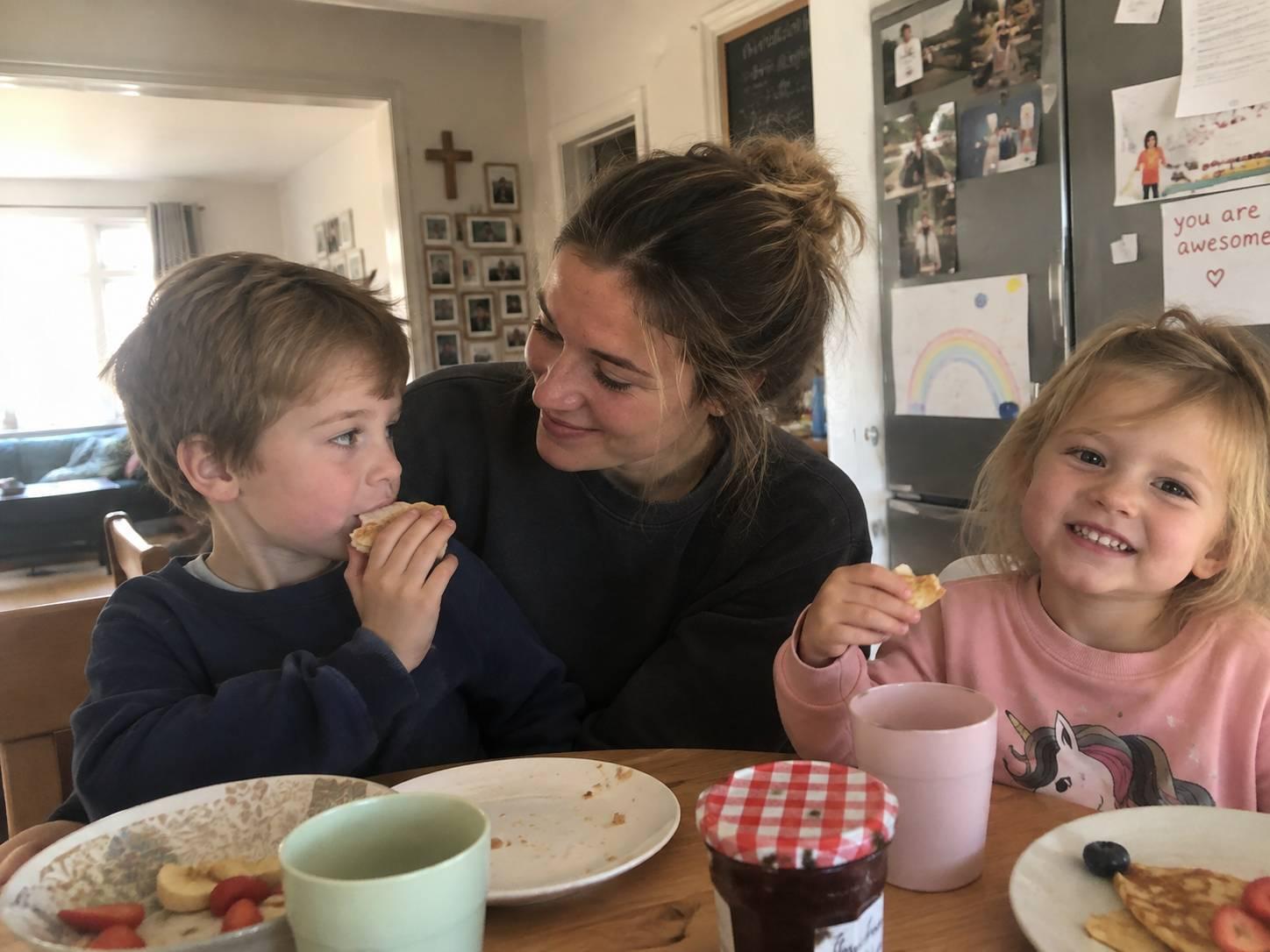 An au pair sitting at the breakfast table with 2 children