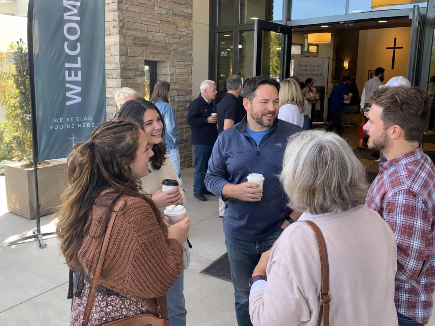 A small group of people outside church talking and having coffee