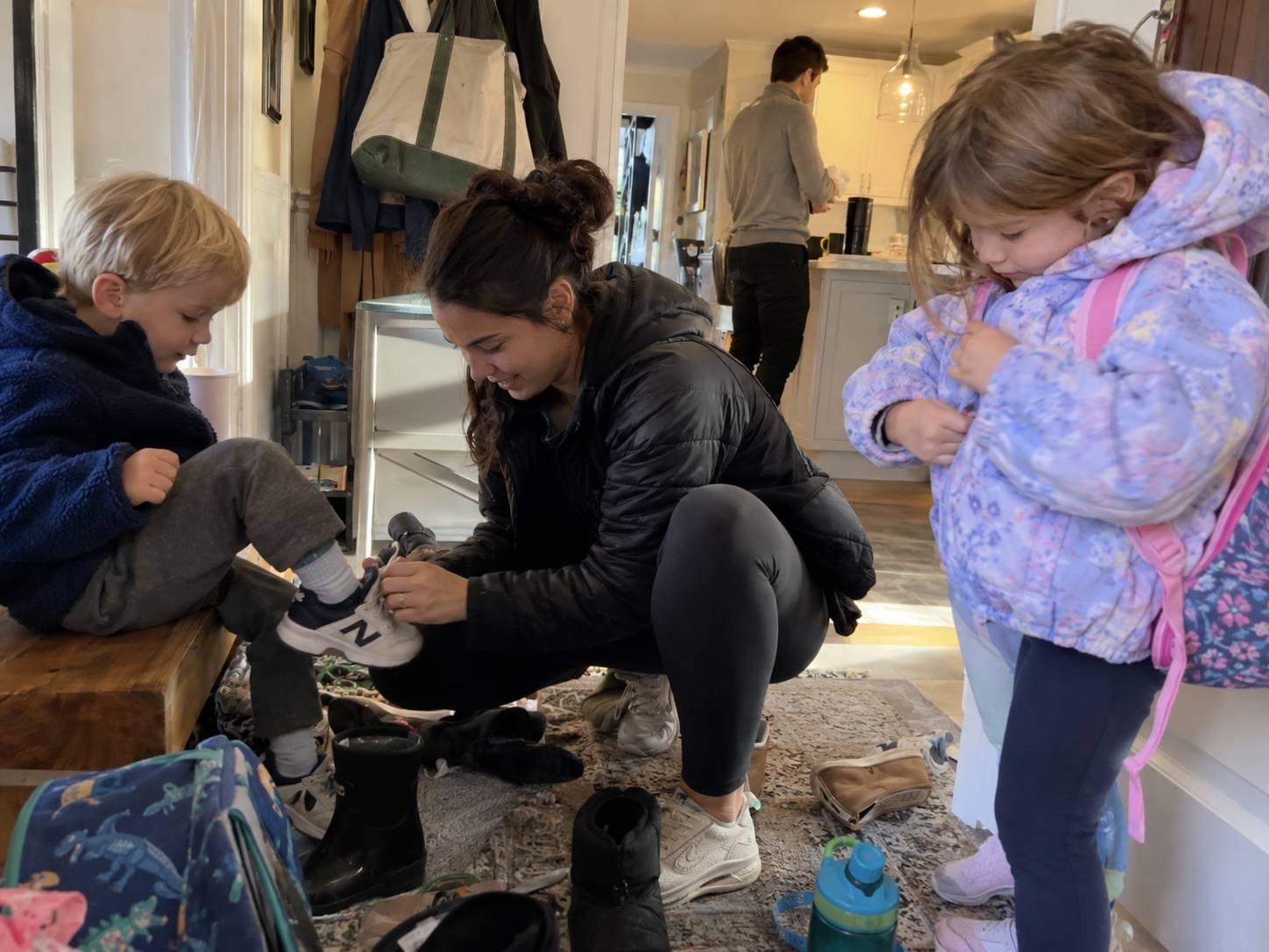 An au pair helping two children get ready for school